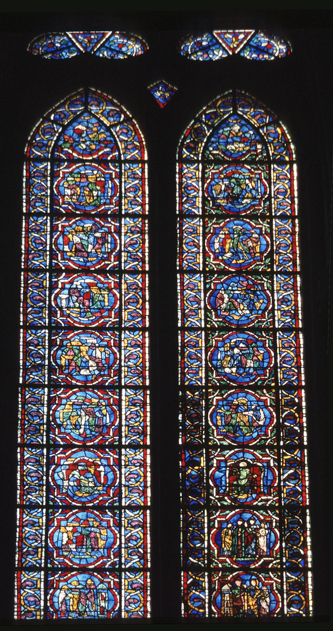 Les trois médaillons anciens situés à la base de la lancette droite, complétés et restaurés, sont accompagnés de médaillons abstraits qui suggèrent des scènes iconographiques.